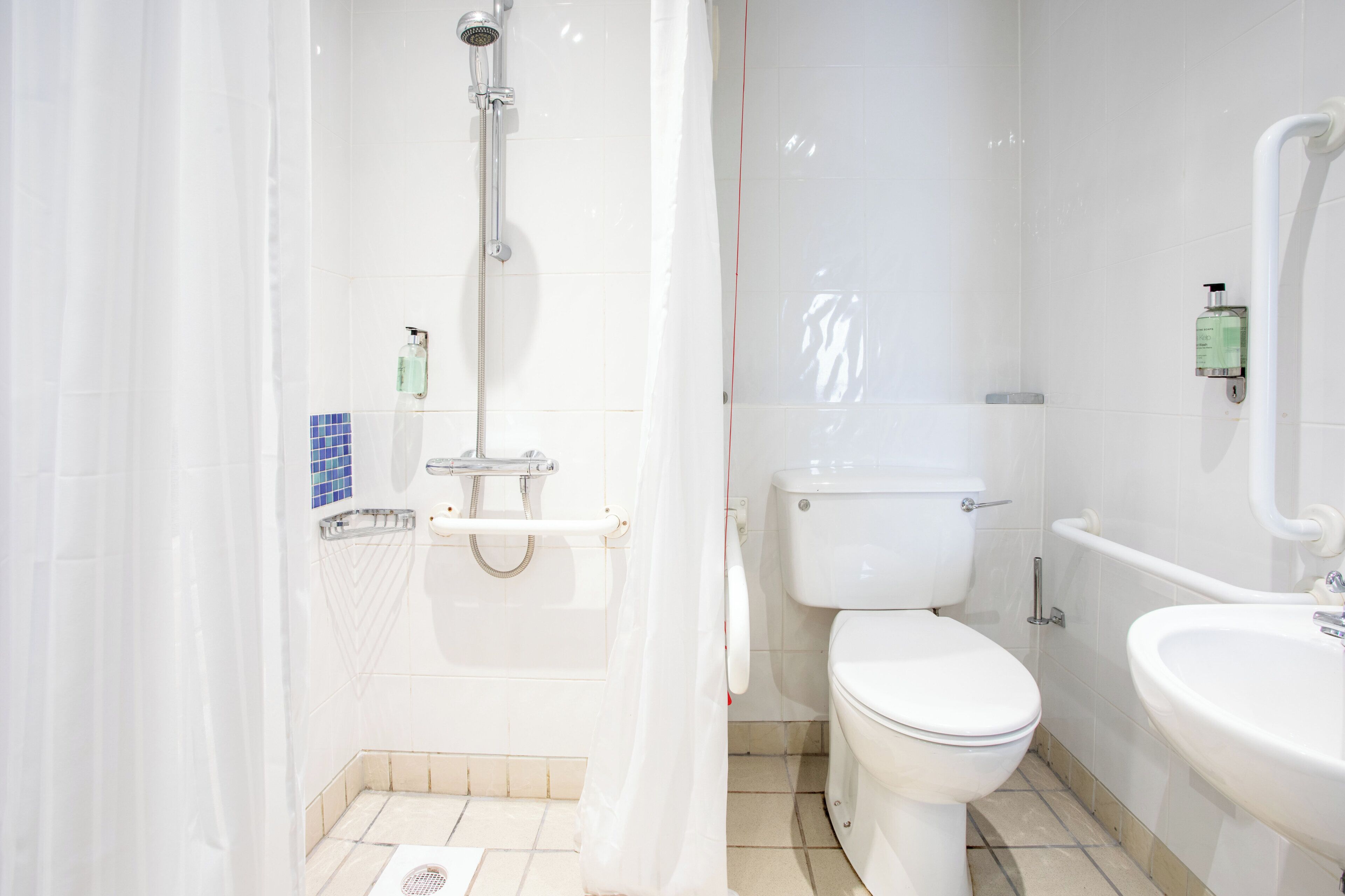 A bathroom with a shower, toilet, and sink.