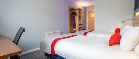 A hotel room with two beds, a desk, and a chair.