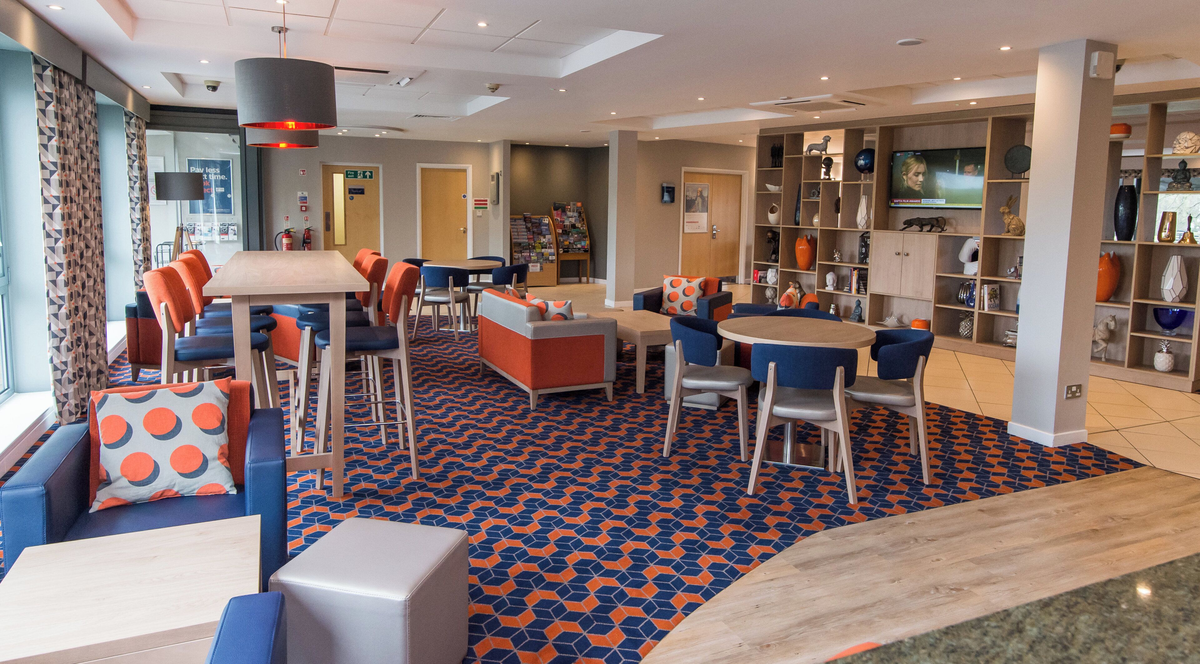 A modern lounge area with seating arrangements, a television, and a patterned floor.