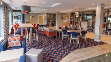 A modern lounge area with seating arrangements, a television, and a patterned floor.