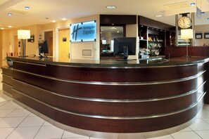 A hotel reception area with a curved reception desk, a digital clock, and a Holiday Inn Express sign.