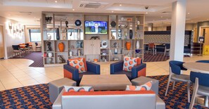 A hotel lobby with seating, a television, and a variety of decorative items on shelves. - Holiday Inn Express Dunfermline by IHG (Dunfermline)