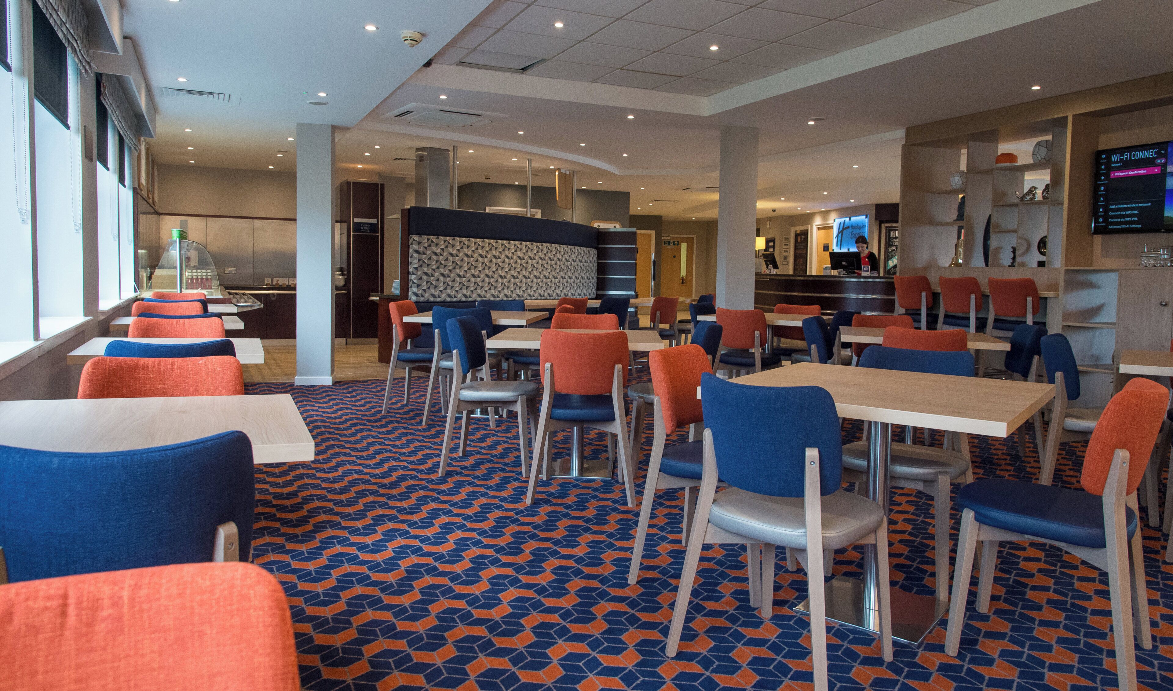 A modern restaurant with multiple seating areas, including booths and tables, and a patterned floor.