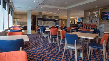A modern restaurant with multiple seating areas, including booths and tables, and a patterned floor.