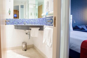 A modern bathroom with a blue-tiled sink, a mirror, and a toilet.