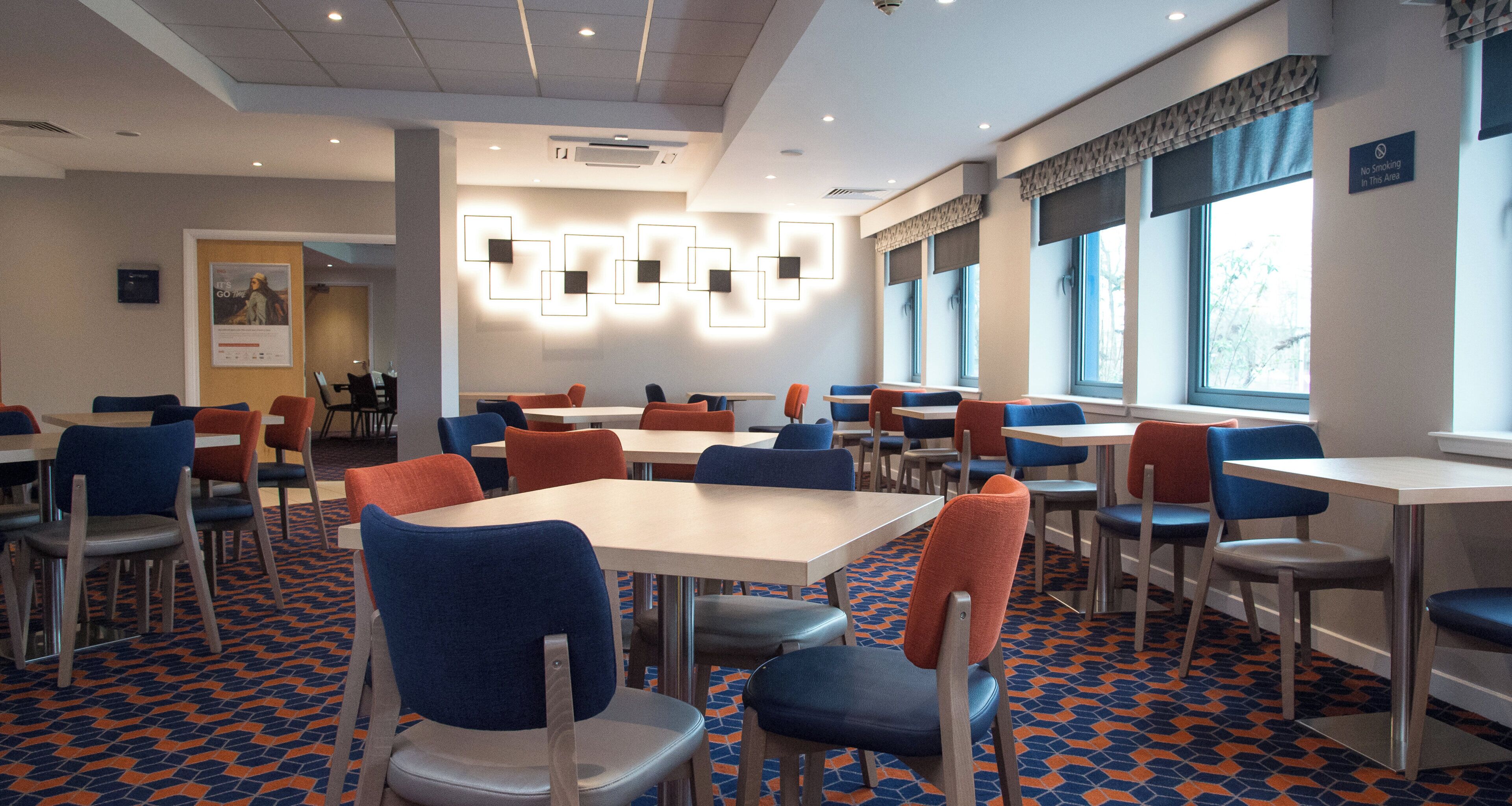 Un espace repas avec des tables et des chaises, un sol à motifs et un panneau « Il est interdit de fumer » accroché au mur.