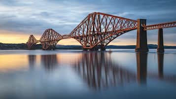 A large steel bridge with a symmetrical design over a calm body of water.