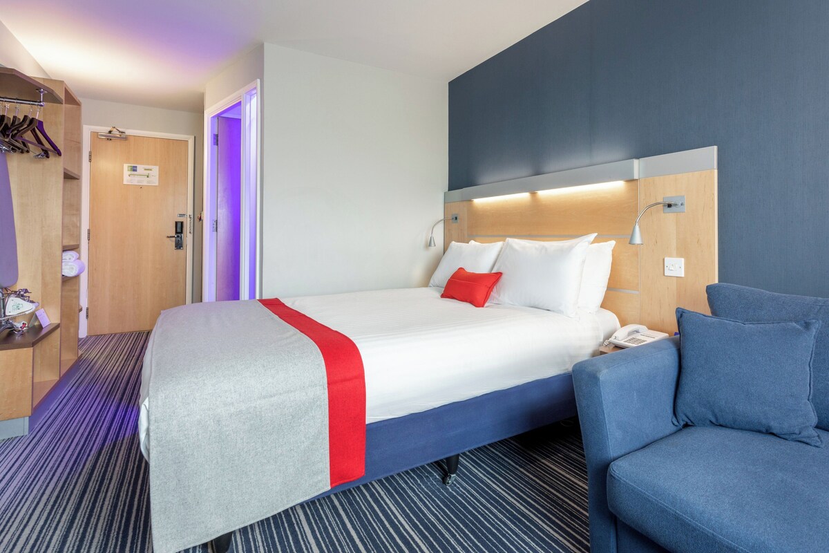 Una habitación de hotel con una cama, un escritorio, una silla y un baño.