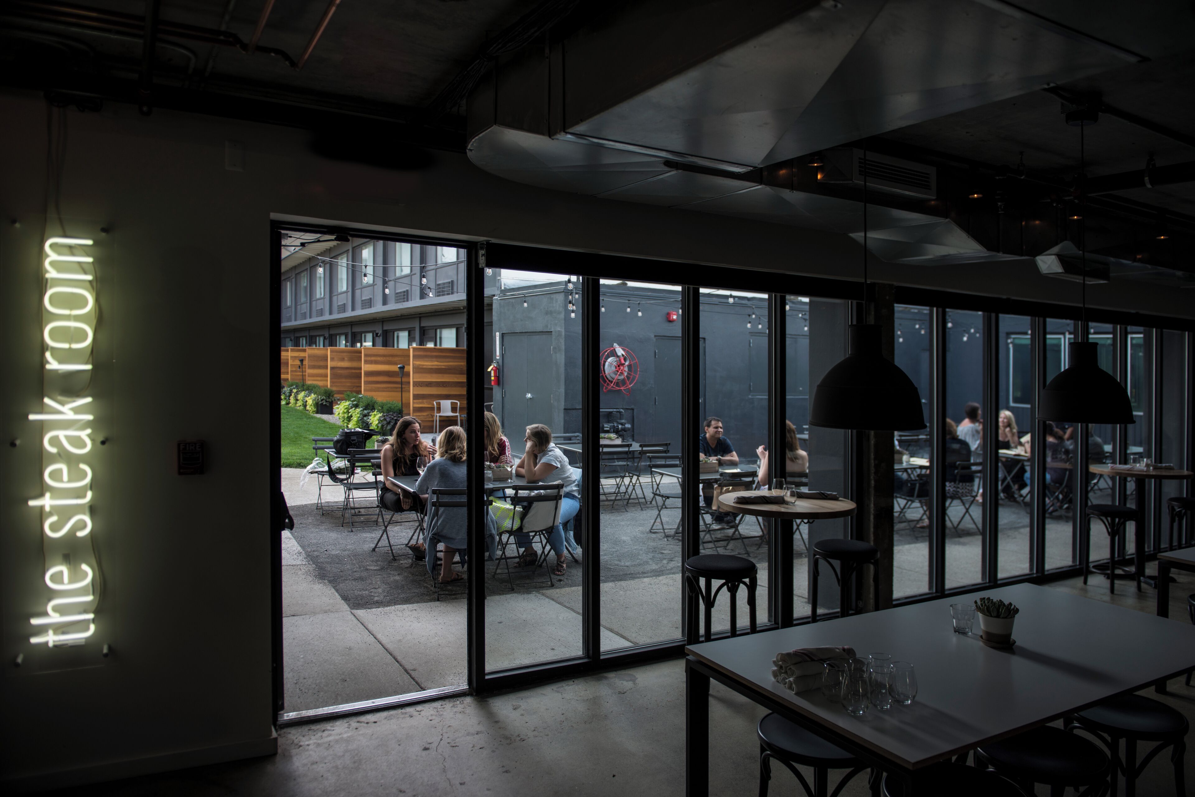 An interior space with a glass wall leading to an outdoor seating area.
