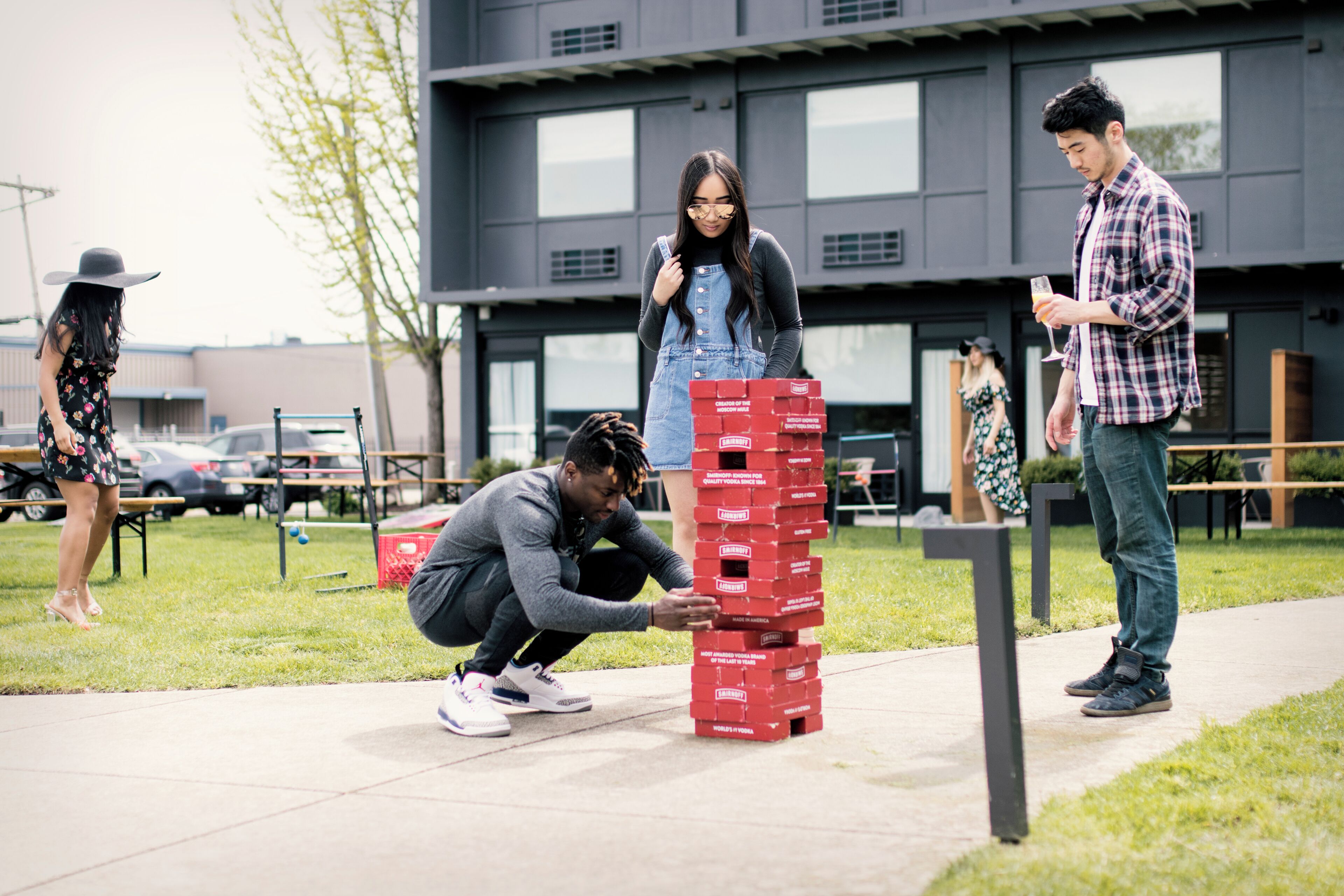 A group of people playing a game with red boxes on a sidewalk.