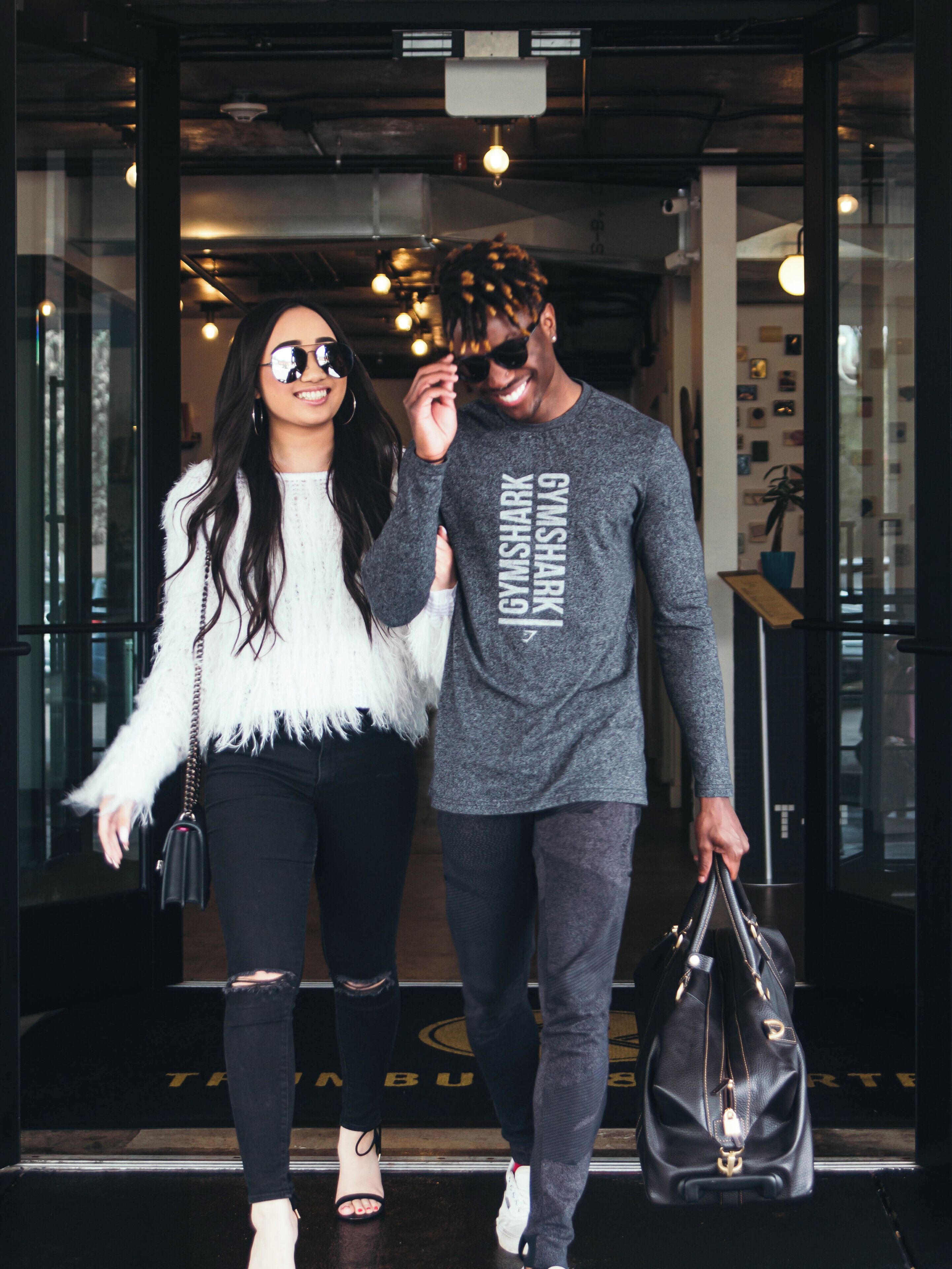 Two individuals walking through a doorway with a sign that reads 'TRIBUNE' on the floor.