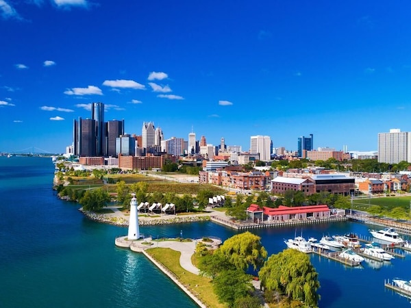 A coastal cityscape with a marina, a lighthouse, and a variety of buildings including high-rise and low-rise structures.