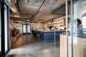 A bar area with stools, a counter, and a variety of bottles.