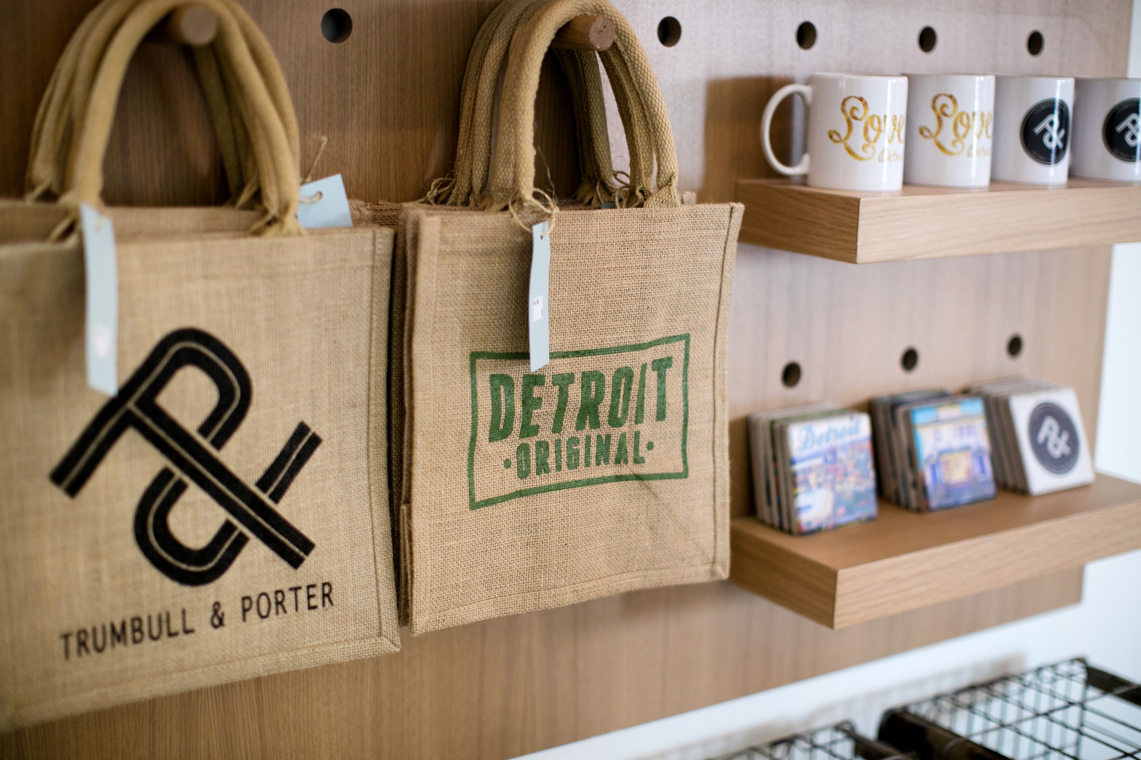 Twee jute zakken hangen aan een prikbord, één met de tekst 'TRUMBULL & PORTER' en de ander 'DETROIT ORIGINAL'.