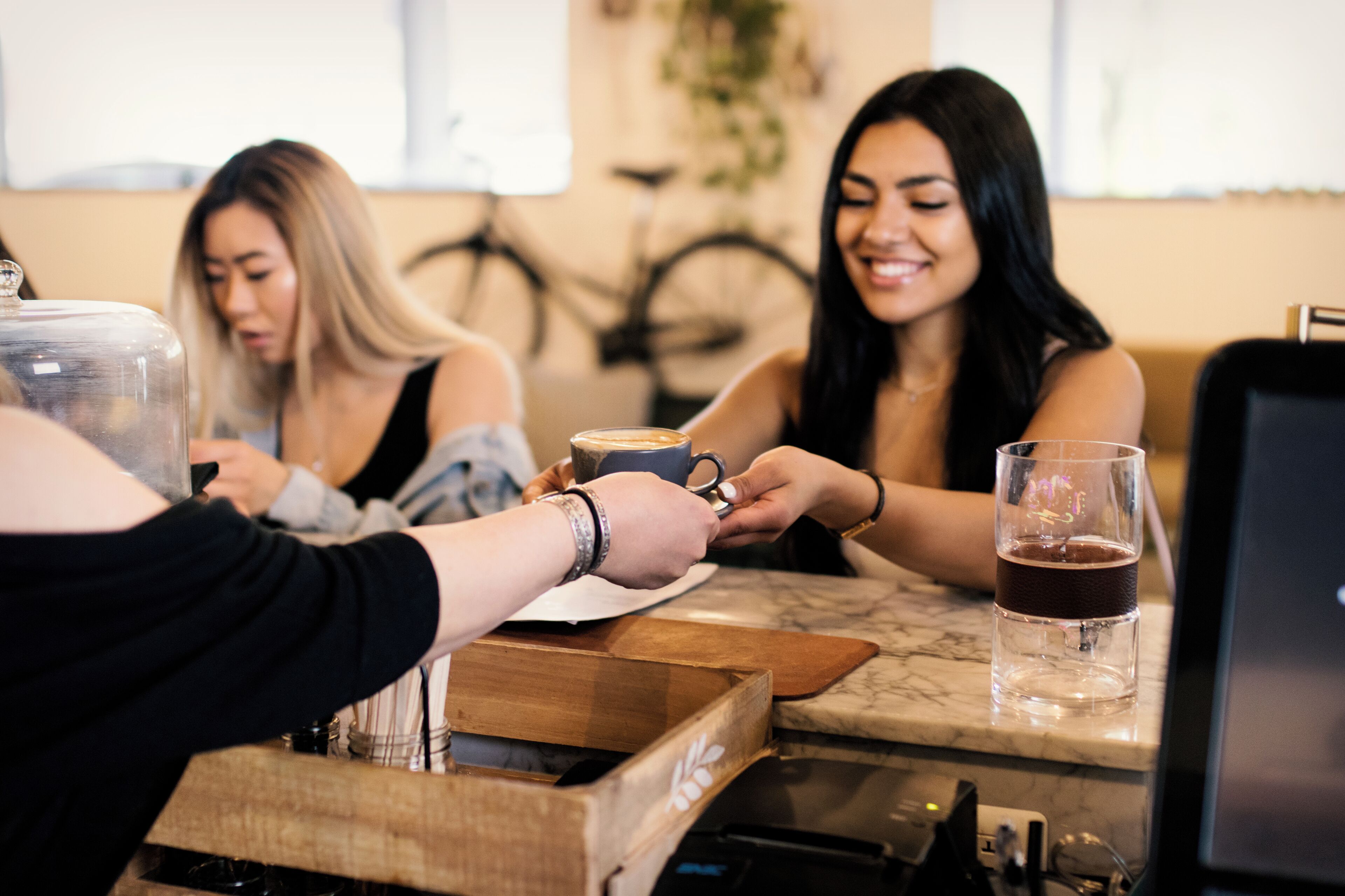 Eine Gruppe von Personen in einem Café mit einer Holztresen und einer Kaffeemaschine.
