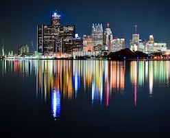 Un horizonte urbano nocturno reflejado en aguas tranquilas.