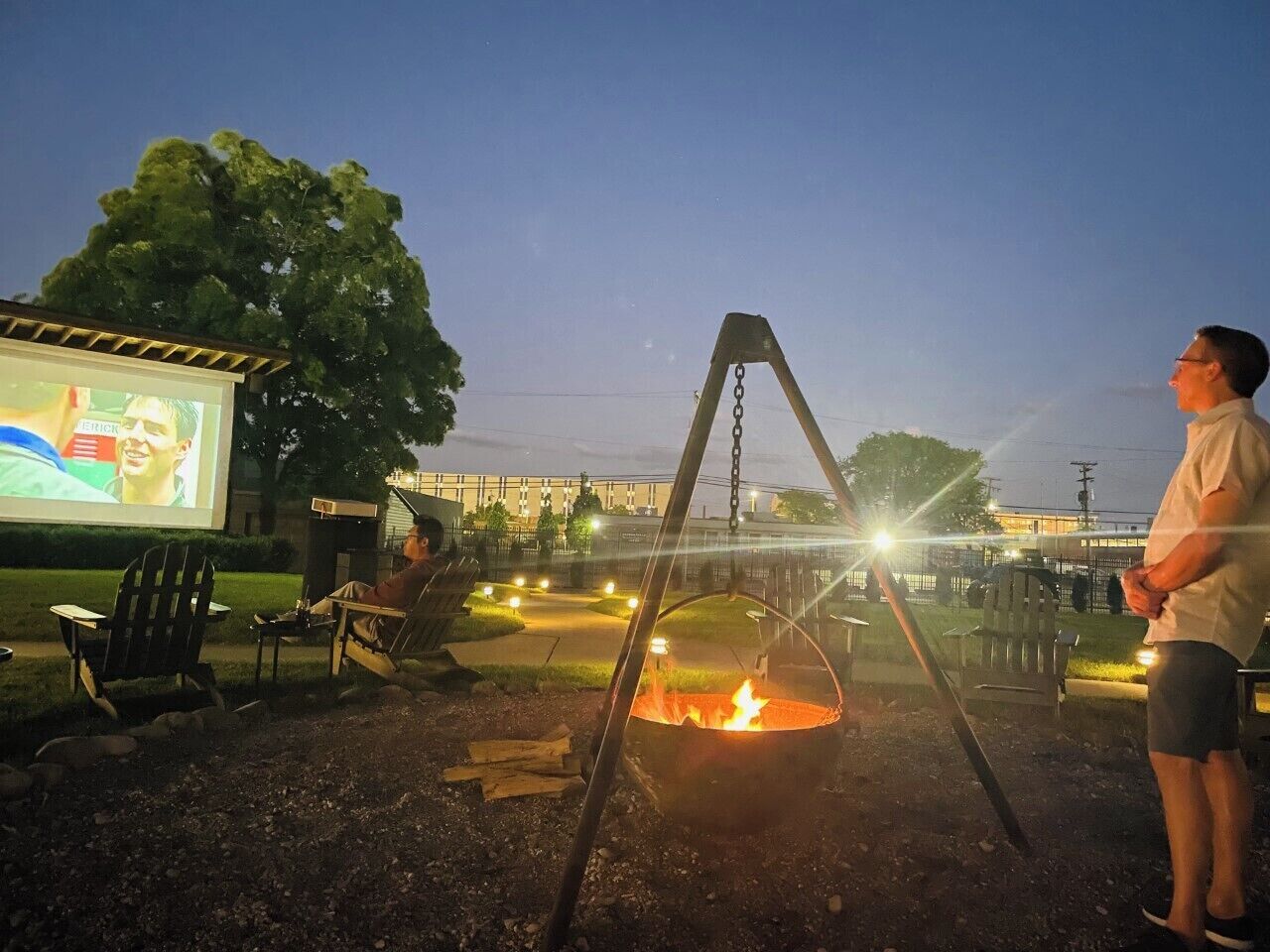 Un área de estar al aire libre con un brasero y una pantalla grande para ver películas.