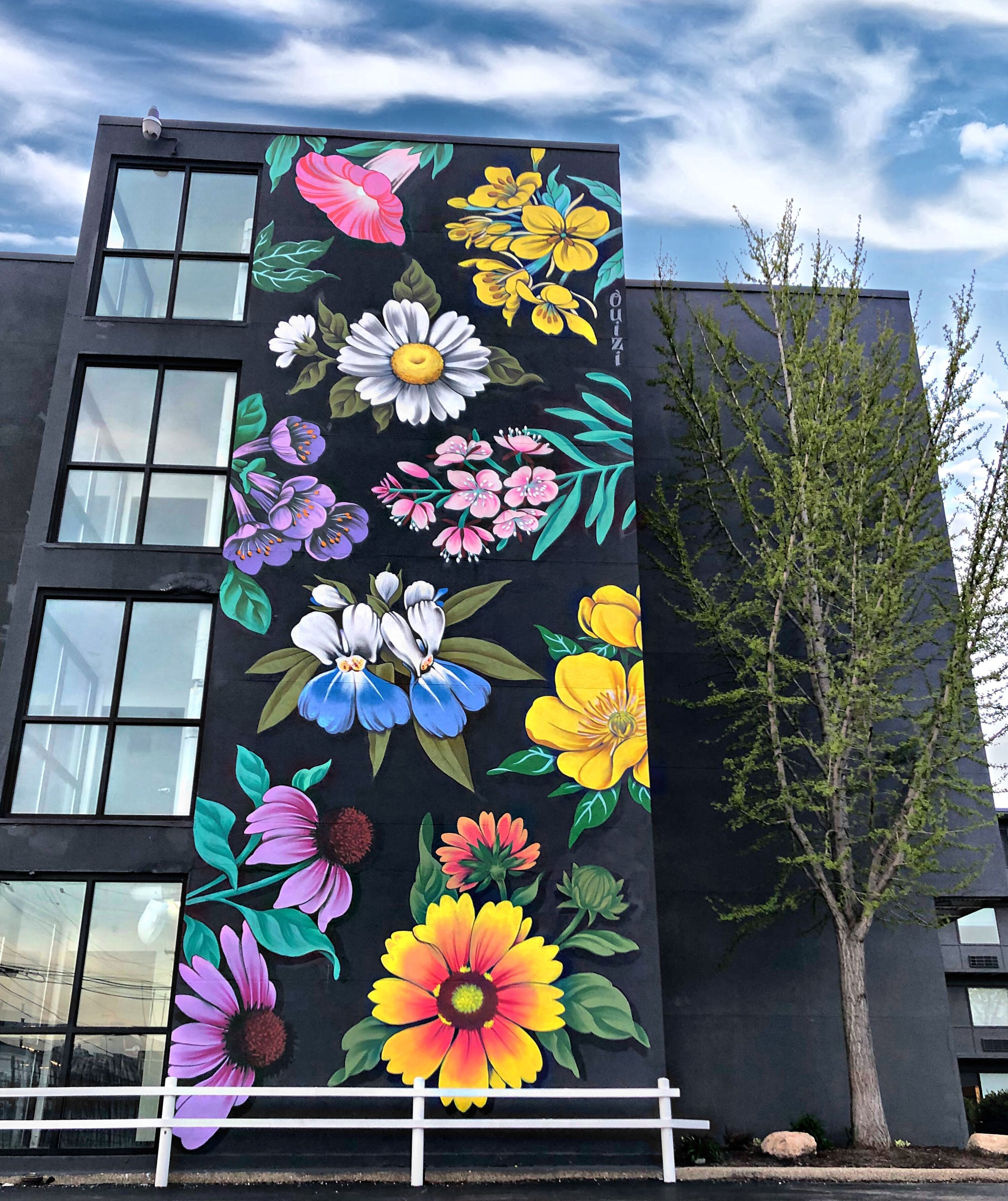 Un edificio con un gran mural de flores coloridas en su fachada.