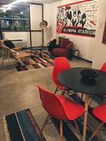 Una habitación con un sofá rojo, una mesa negra y un cartel de Los Rolling Stones en la pared.