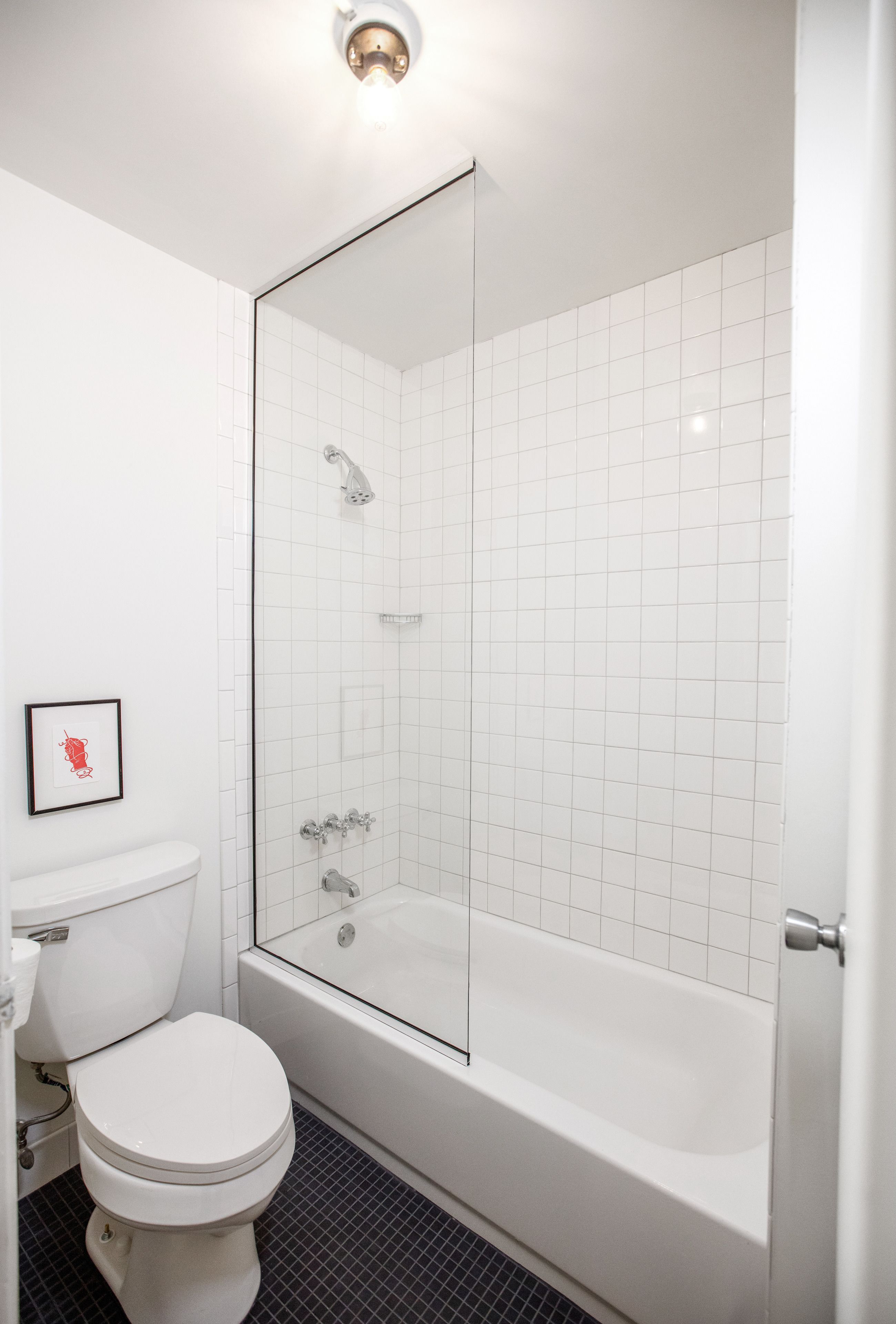 A modern bathroom with a white toilet, a glass-enclosed shower, and a white bathtub.