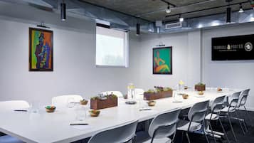 A conference room with a long table, white chairs, and artwork on the walls.