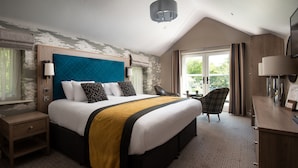 A hotel room with a large bed, a desk, a chair, and a balcony with curtains. - Windermere Rooms at The Wateredge Inn (Ambleside)