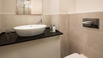 A modern bathroom with a large white sink, a mirror above it, and a glass shower enclosure.