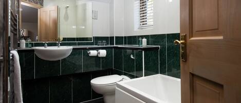 A bathroom with a white sink, toilet, and bathtub, and a mirror above the sink.