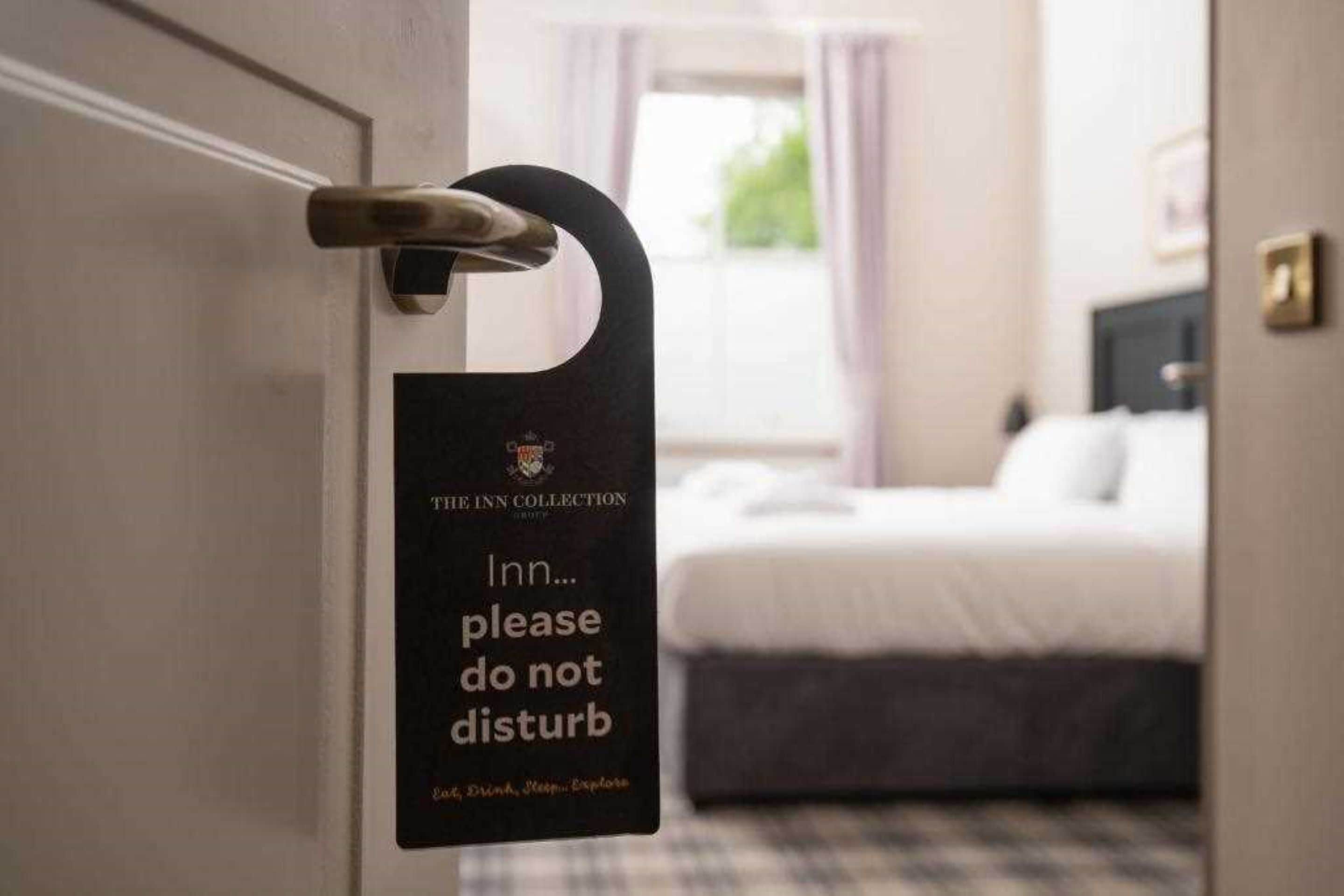 A hotel room door with a sign that reads "The Inn Collection: Inn... please do not disturb."
