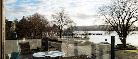 A view from a balcony with wicker chairs and a table, overlooking a body of water and a bridge.