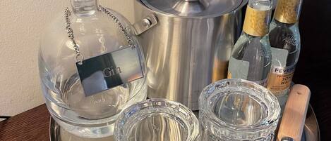 A silver tray with a glass decanter, a metal pot, two bottles of champagne, and two crystal glasses.