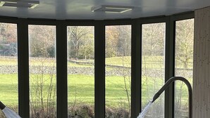 Un jacuzzi con chorros de agua en una habitación con ventanas amplias que dan a una zona verde.