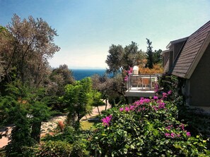 A residential area with a balcony overlooking a garden and a view of the sea.
