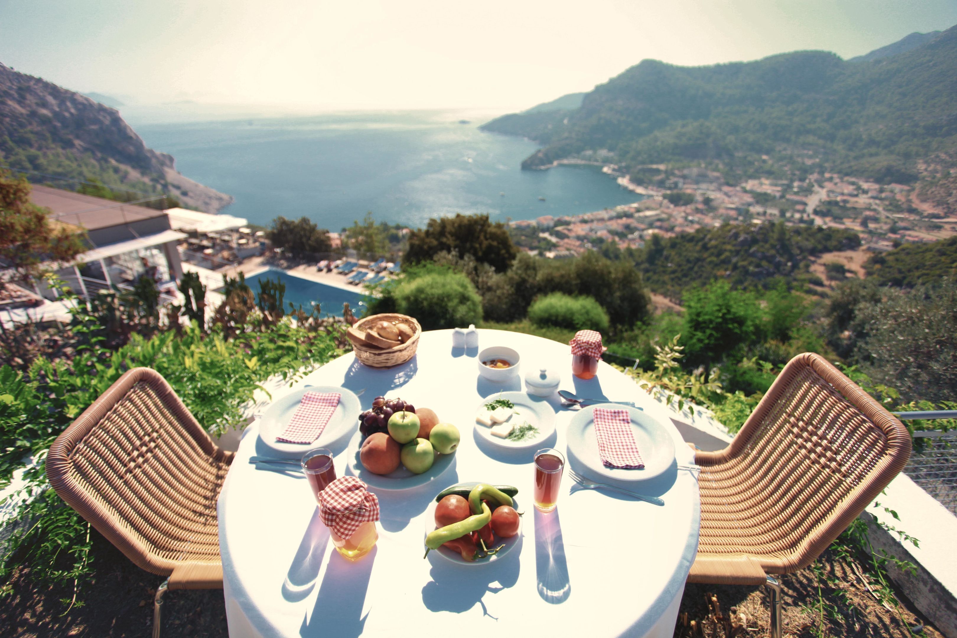 Ein Tisch ist für eine Mahlzeit gedeckt, mit Blick auf eine malerische Küstenlandschaft.