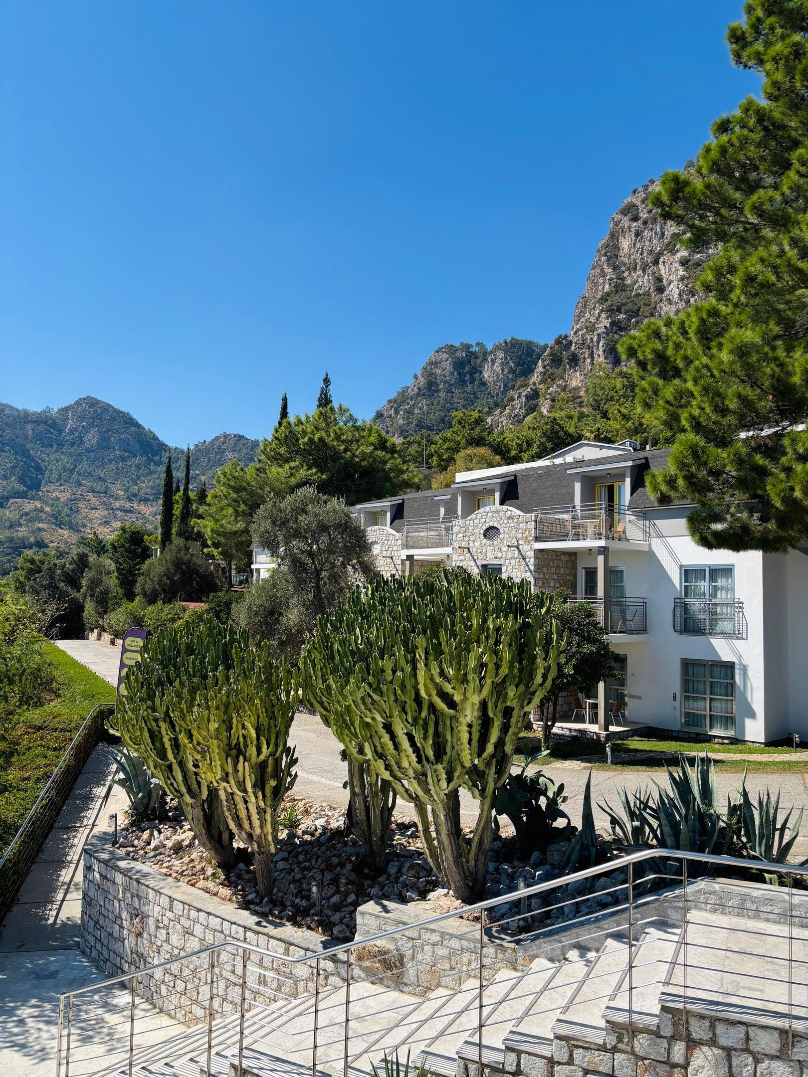 A hotel with a stone facade, multiple balconies, and a mountainous backdrop.