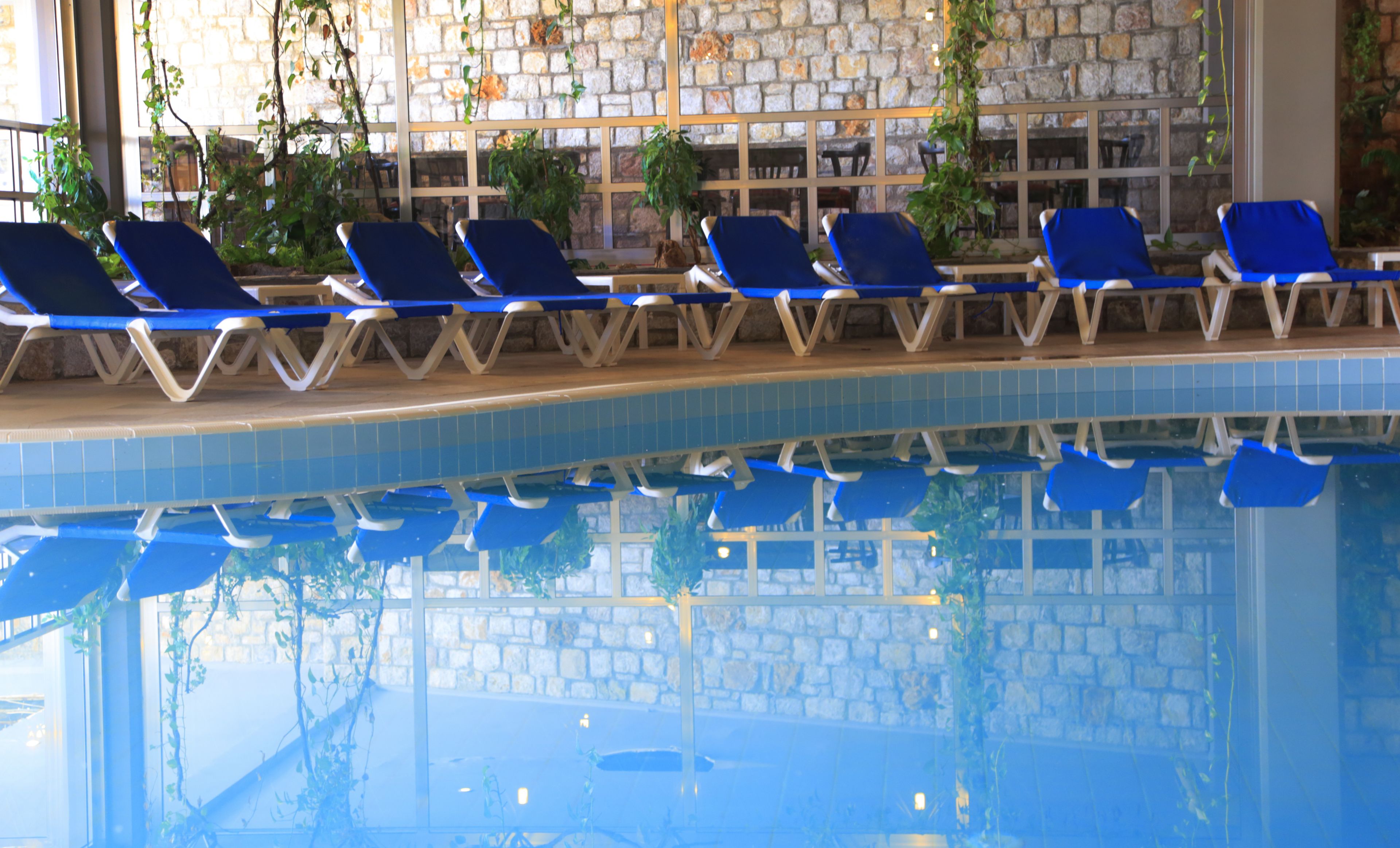 A pool area with blue lounge chairs and stone walls.