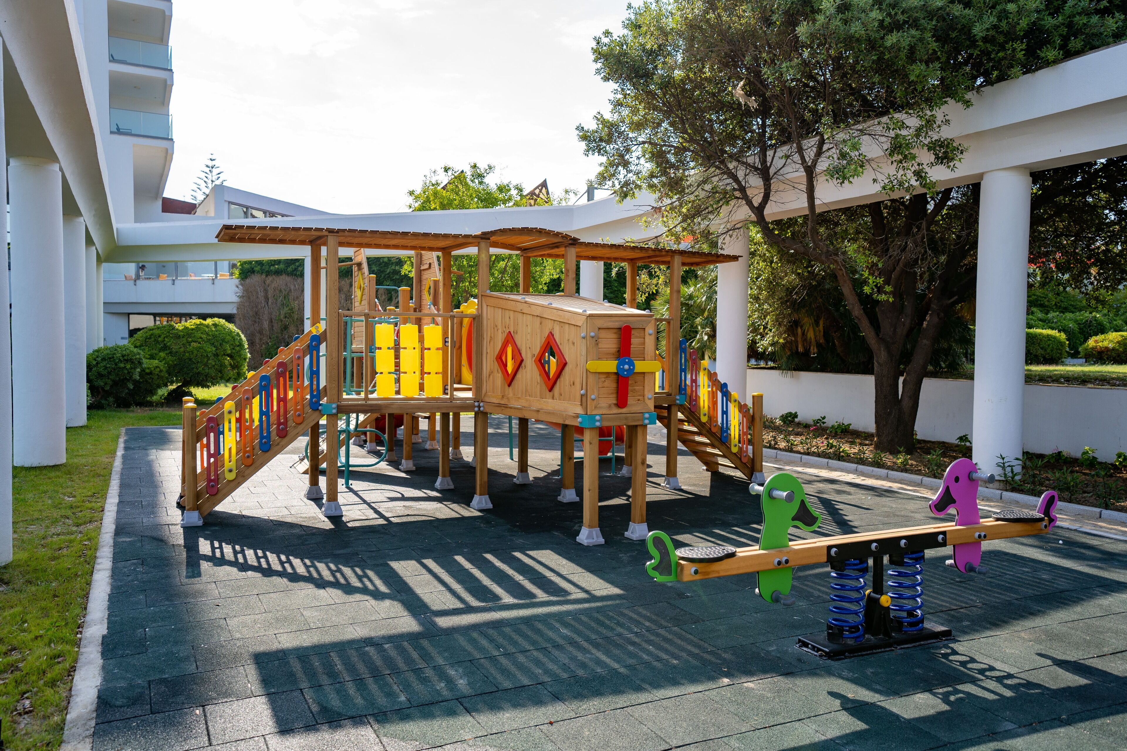A playground with a wooden structure, slides, and swings.