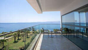 A balcony with a glass railing overlooking a body of water and greenery. - Grand Hotel Ontur (Cesme)