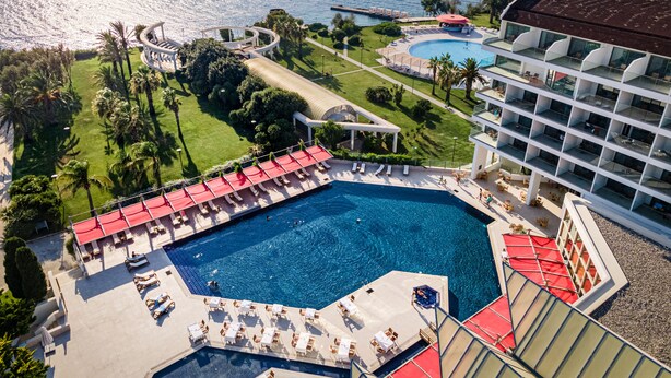 A resort with a large pool, sun loungers, and a view of the ocean. - Grand Hotel Ontur (Cesme)