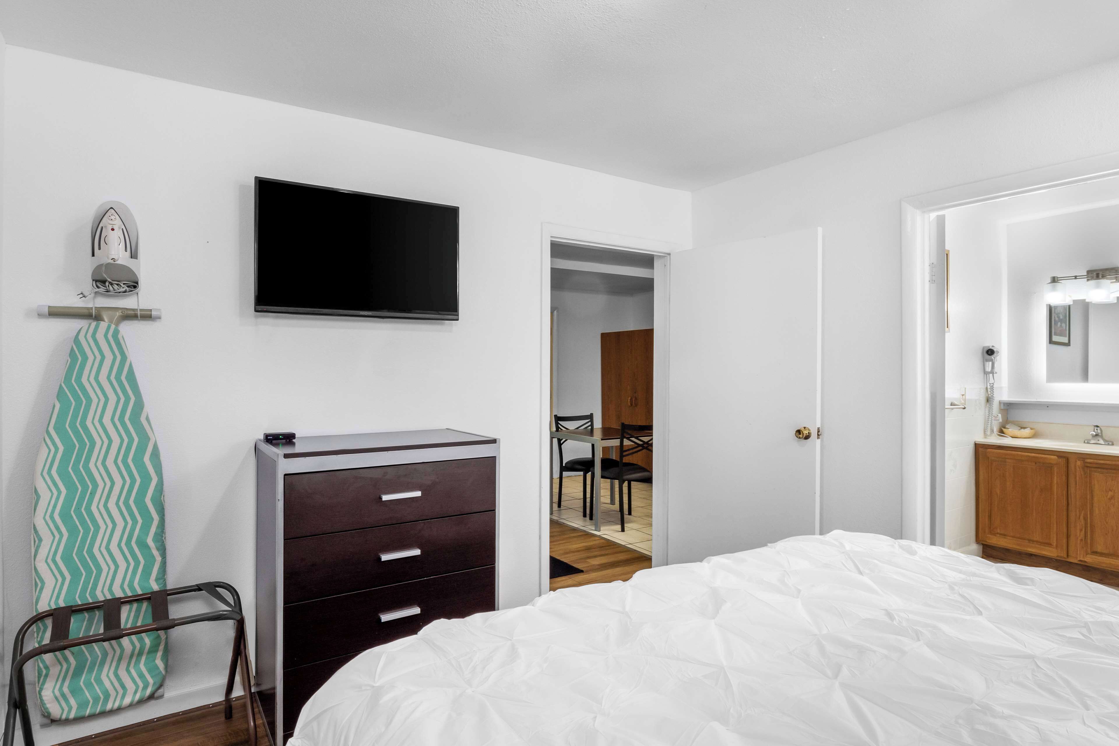 Un dormitorio con cama, cómoda, televisor y espejo.