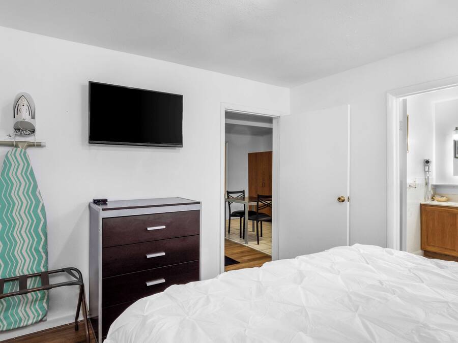 Un dormitorio con cama, cómoda, televisor y espejo.