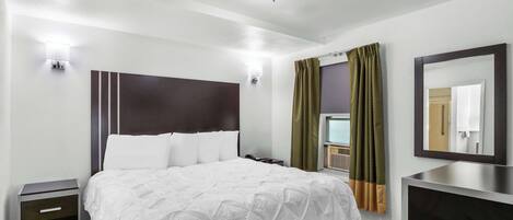 Una habitación de hotel moderna con una cama grande, mesitas de noche, un espejo y una ventana con cortinas.
