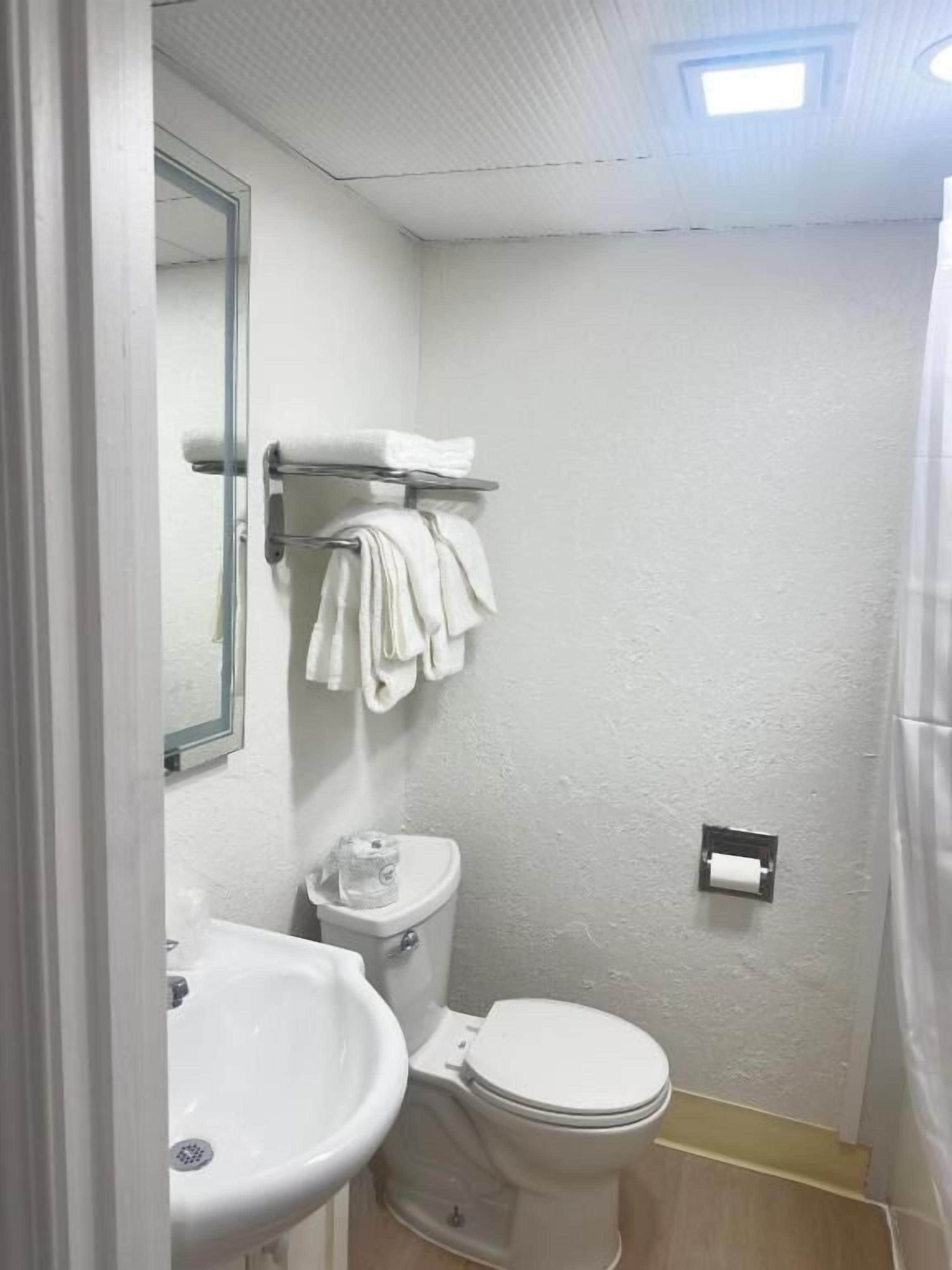 A small, clean bathroom with a toilet, sink, and towel rack.