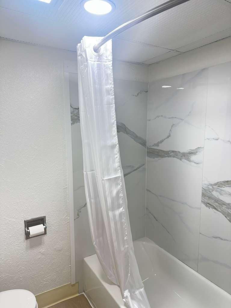 A bathroom with a shower curtain, a toilet, and marble-patterned walls.