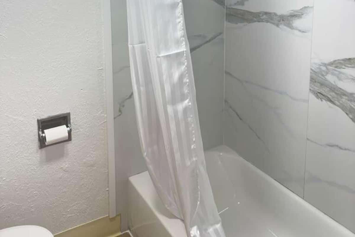 A bathroom with a shower curtain, a toilet, and marble-patterned walls.