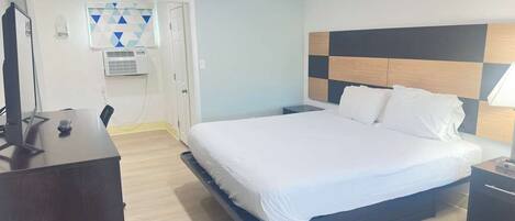 A hotel room with a bed, bedside table, desk, and a television.