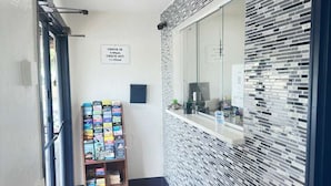 A hallway with a check-in sign, a book display, and a window with a view. - Bourne Bridge Inn  (Buzzards Bay)