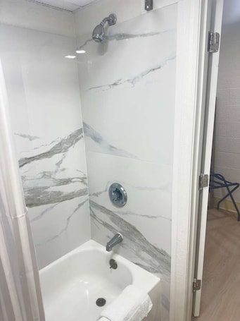 A bathroom with a shower, a sink, and a marble wall.. Bourne Bridge Inn