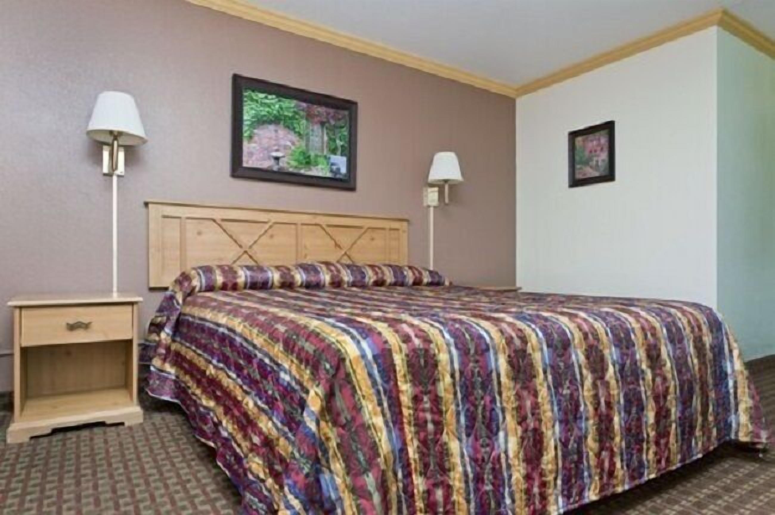A hotel room with a bed, two bedside tables, and two wall-mounted lamps.
