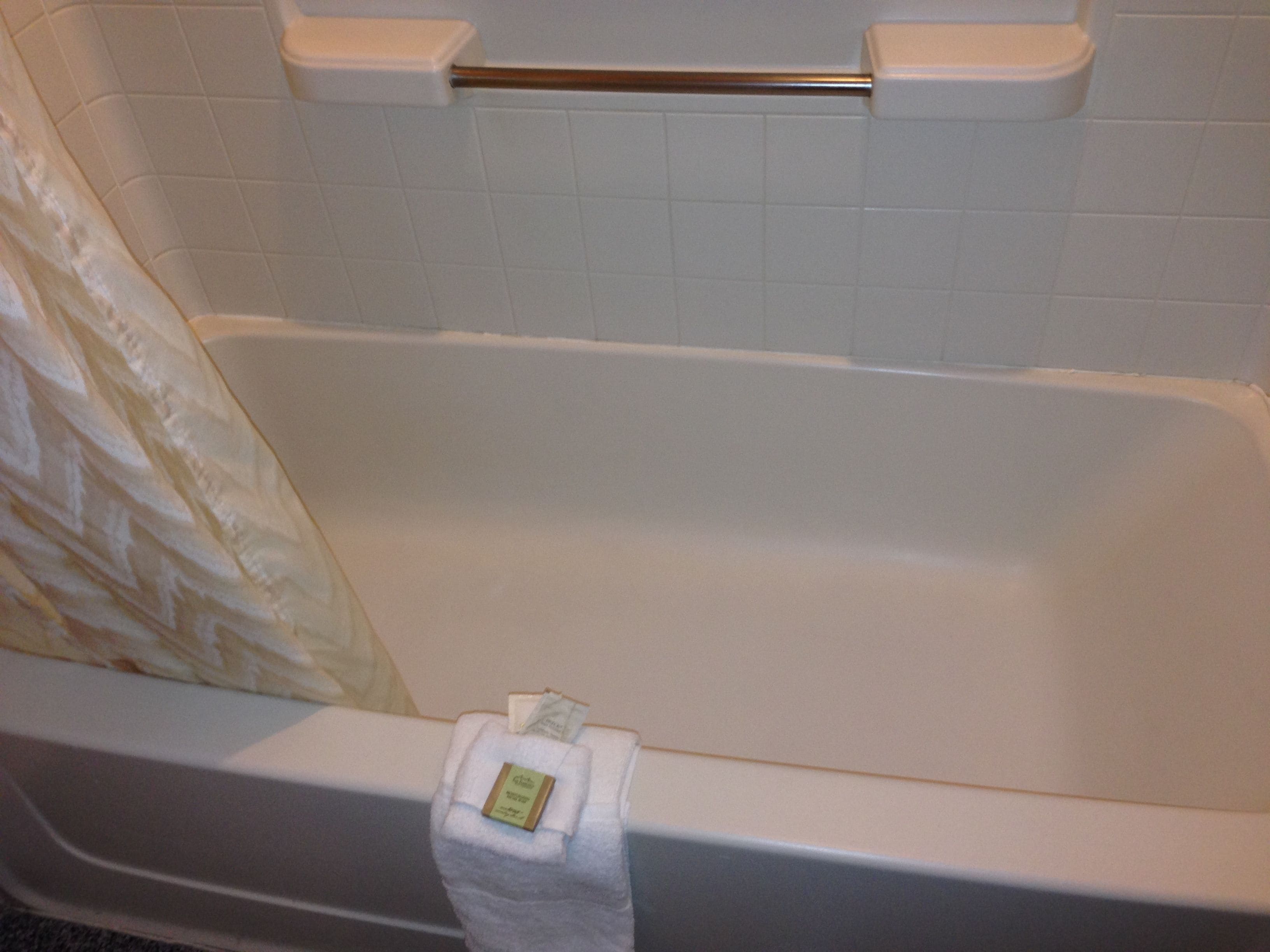 A bathtub with a towel rack and a shower curtain.